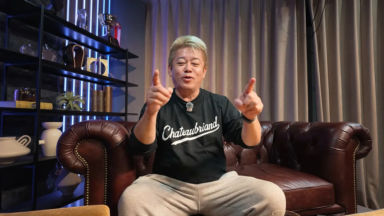 動画の画面。堀江貴文さんがソファに座り、両手で指さしながら話している