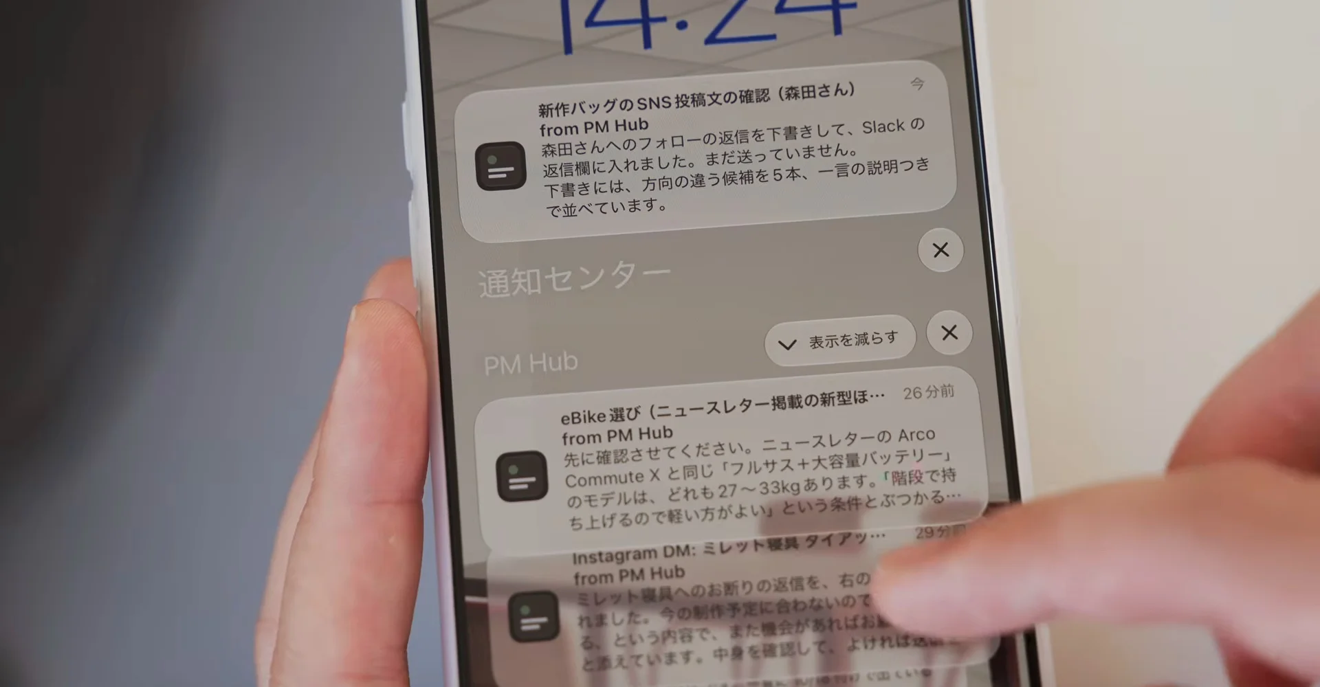 動画の画面。スマホの通知センターに、PM Hub からの通知が3件並び、手で指している。