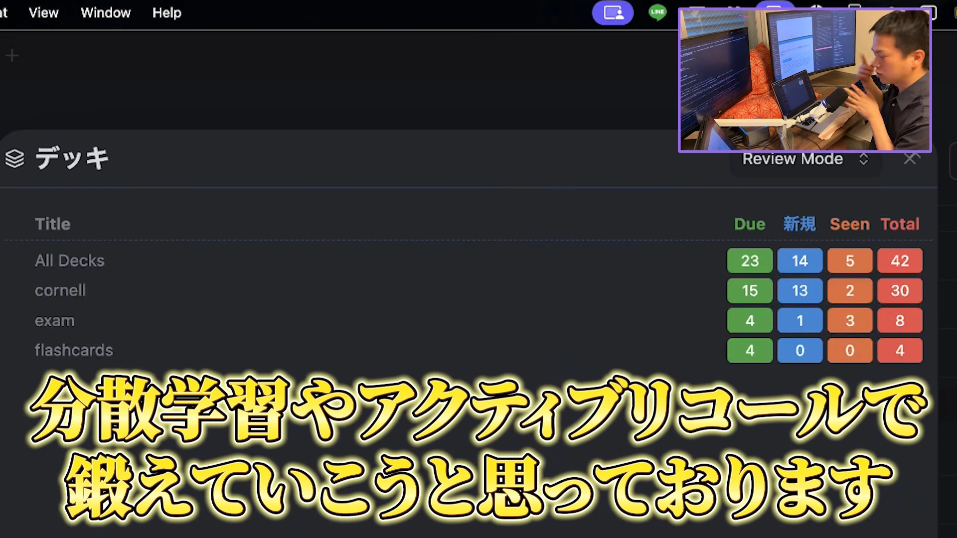 動画の画面。Obsidianのフラッシュカードのデッキ一覧に、All Decks・cornell・exam・flashcards の4行と、Due・新規・Seen・Total の枚数が映っている場面。All Decks は合計42枚。右上に机で作業する飯塚さんの小窓。字幕は「分散学習やアクティブリコールで鍛えていこうと思っております」