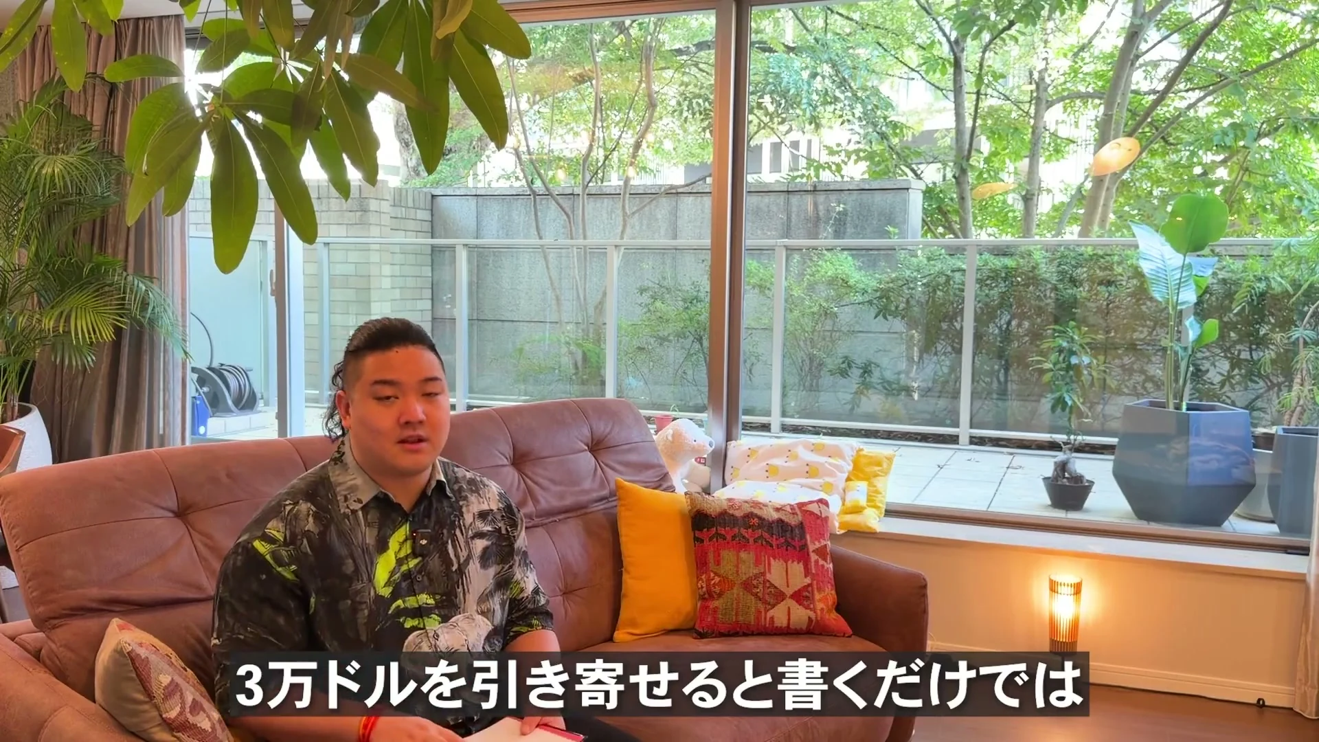 新居のリビングのソファで、3万ドルと書くだけでは足りない、という話をしている動画の場面