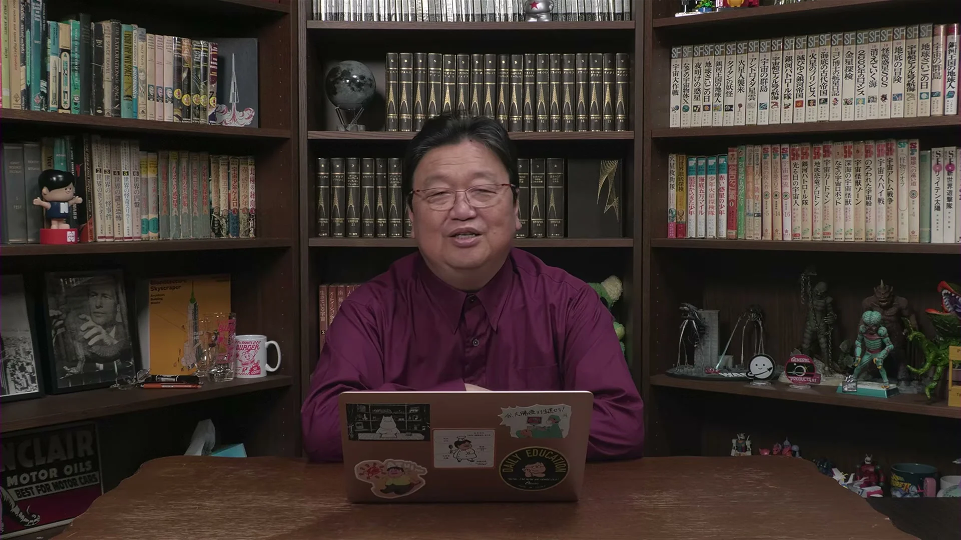 紫のシャツ姿の岡田斗司夫さんが、書棚の前で4年後の追加コメントを話している動画の場面