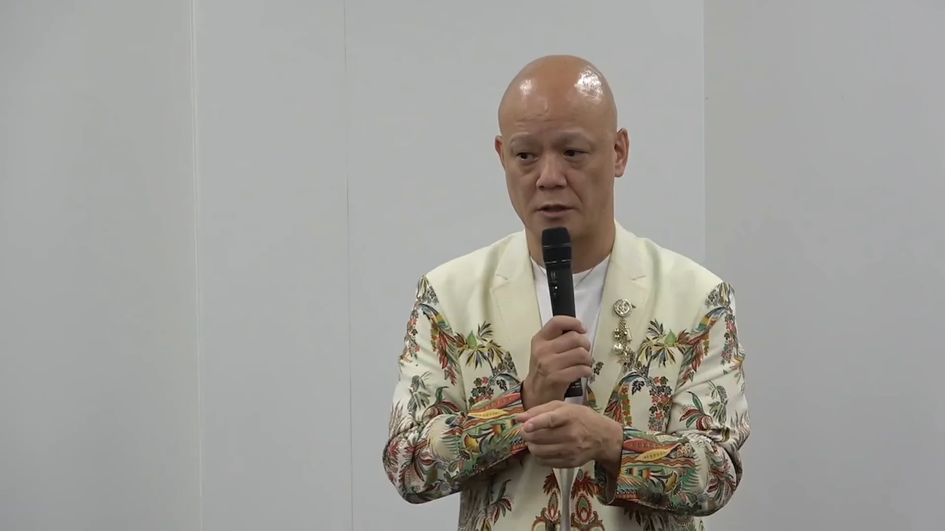 鴨頭嘉人さんが右手にマイクを持ち、左手を添えて、編集力について語り始める講義の場面