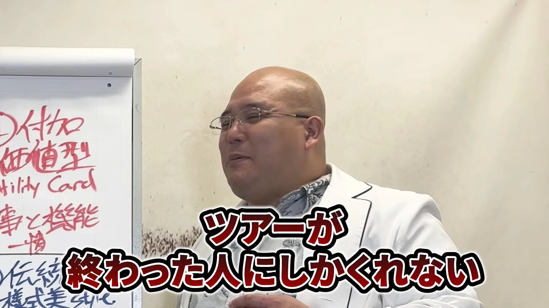 動画の画面。ホワイトボードの前で白衣の人が話し、字幕に「ツアーが終わった人にしかくれない」と出る。ボードには「付加価値型」「仕事と機能一貫」の文字が見える