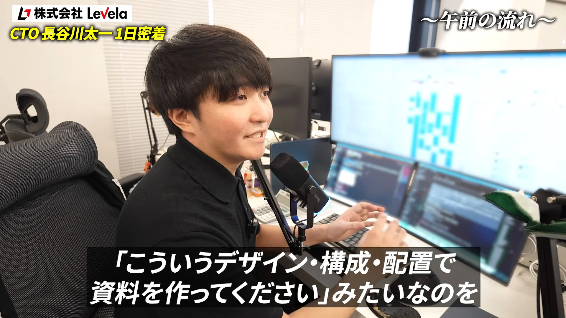 動画の字幕「こういうデザイン・構成・配置で資料を作ってください」。複数のモニターが並ぶデスクで話す長谷川さん