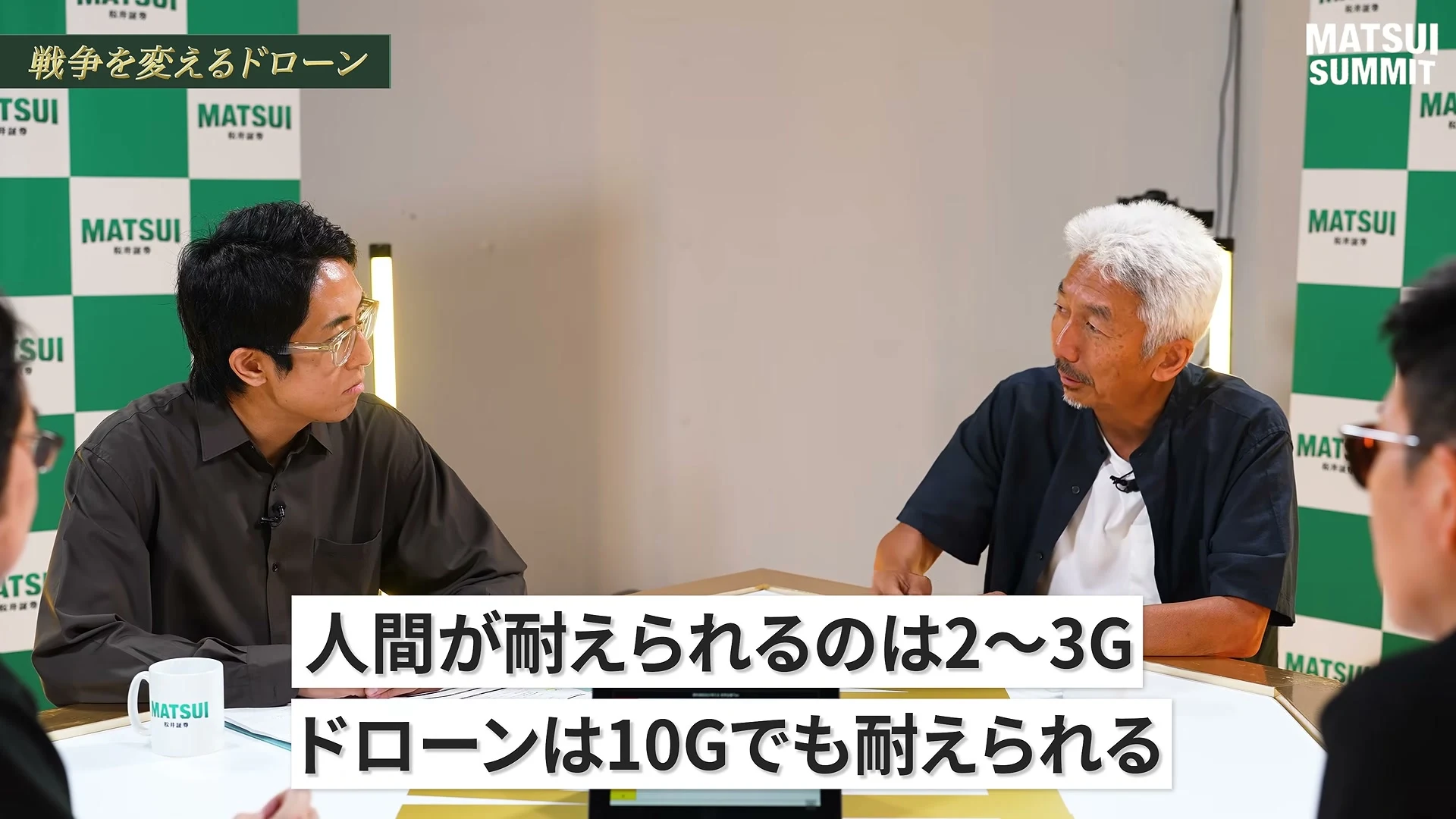 動画の画面。左上に、戦争を変えるドローン、の題。中島聡さんが左を向いて話し、画面下の字幕に、人間が耐えられるのは2〜3G、ドローンは10Gでも耐えられる、と出ている。