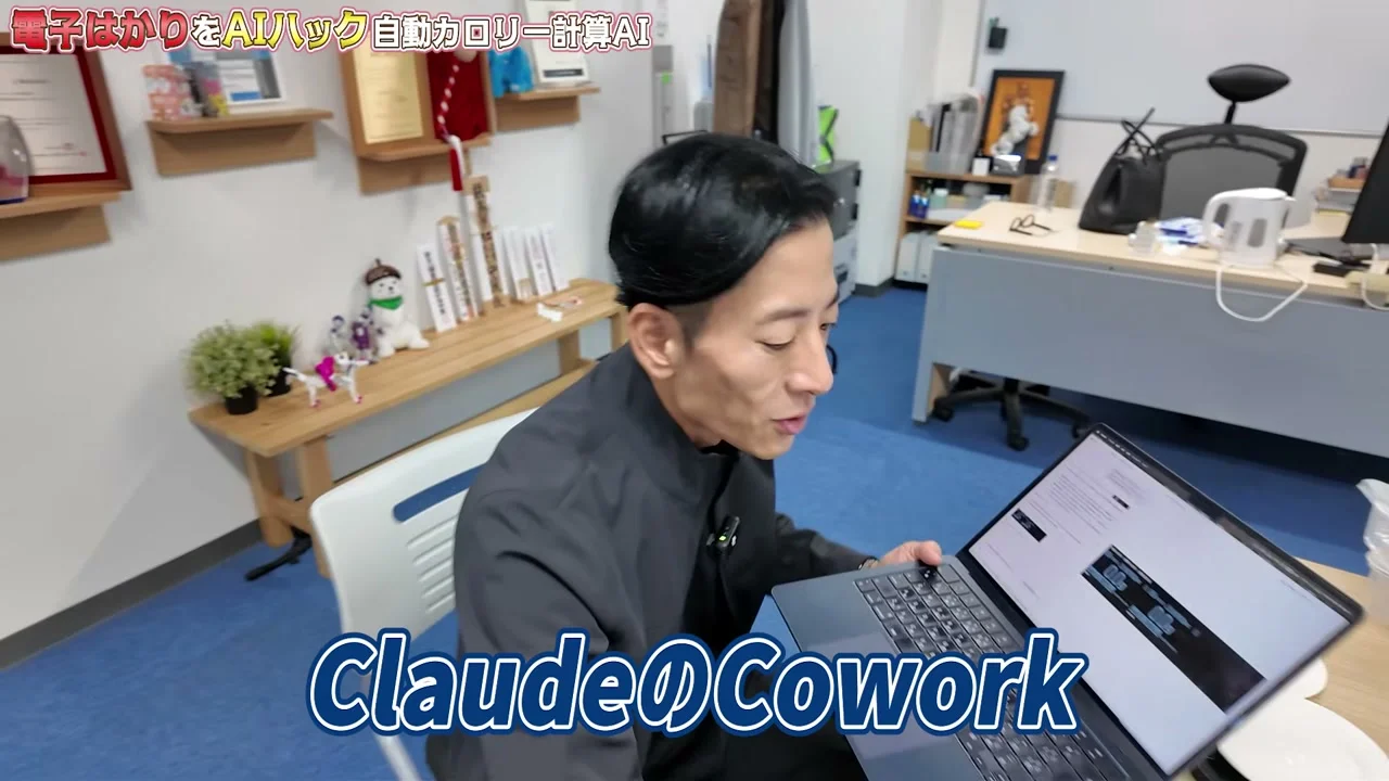 動画キャプチャ: ノートPCを開いて開発を説明する場面。ClaudeのCoworkのテロップが出る(5:18頃)
