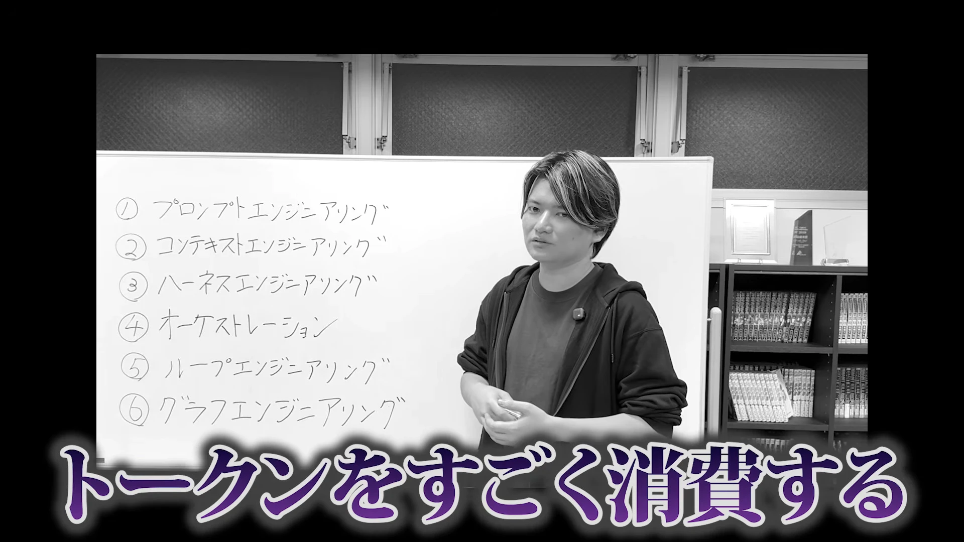 白黒の画面で、ホワイトボードの前に立つ人の下に、トークンをすごく消費する、と字幕が出た動画の場面