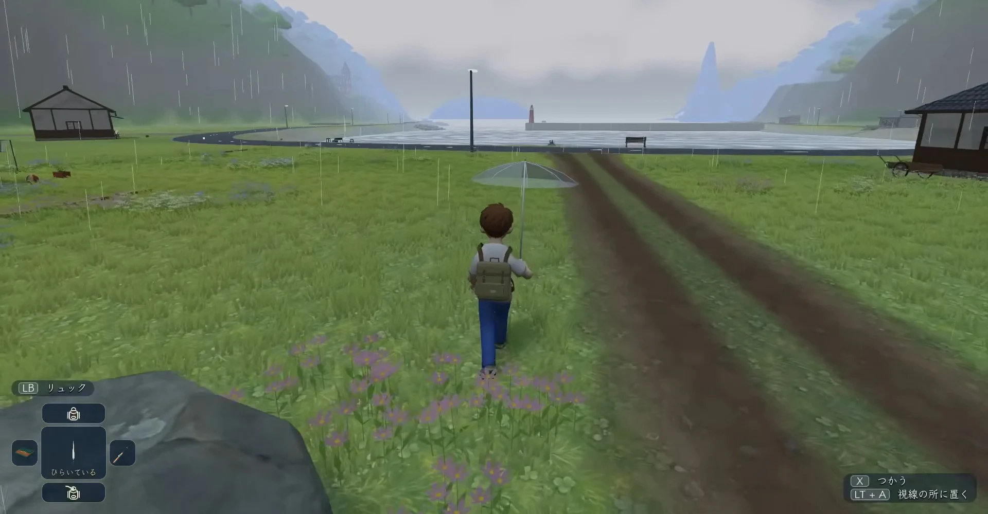 動画のゲーム画面。雨の降る入り江の草地を、リュックを背負った少年が傘をさして奥へ歩く後ろ姿。奥に灯台と海、右に土の道が見える
