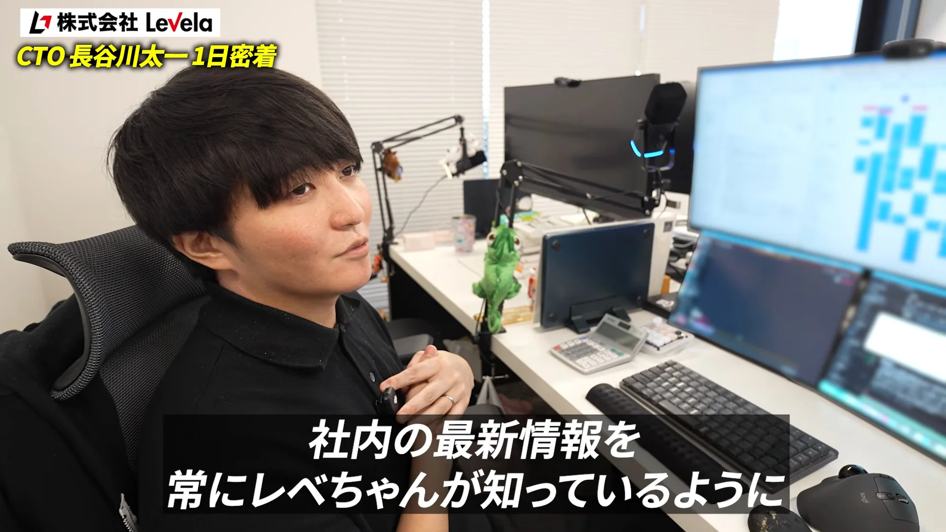 動画の字幕「社内の最新情報を常にレベちゃんが知っているように」。複数のモニターが並ぶデスクで話す長谷川さん