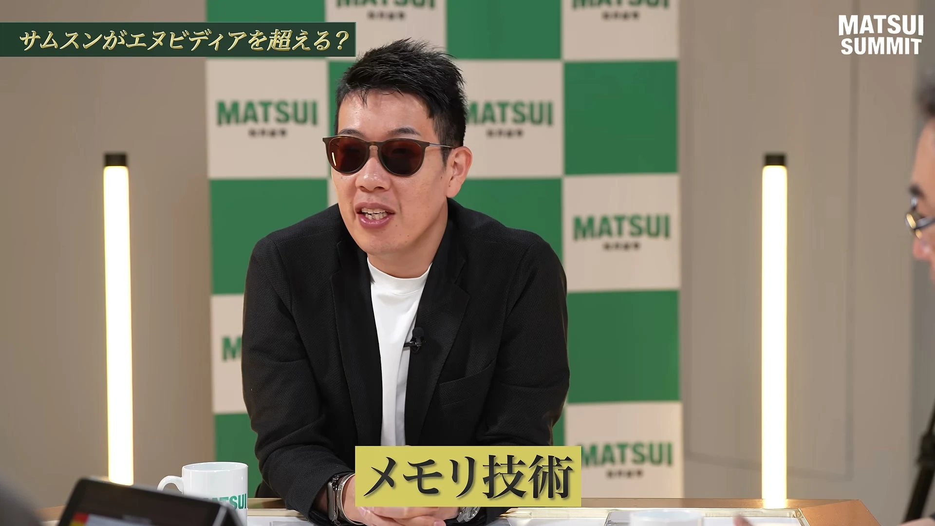 動画の画面。左上に、サムスンがエヌビディアを超える？、の題。サングラスのものづくり太郎さんが身を乗り出して話し、画面下に、メモリ技術、の字幕が出ている。