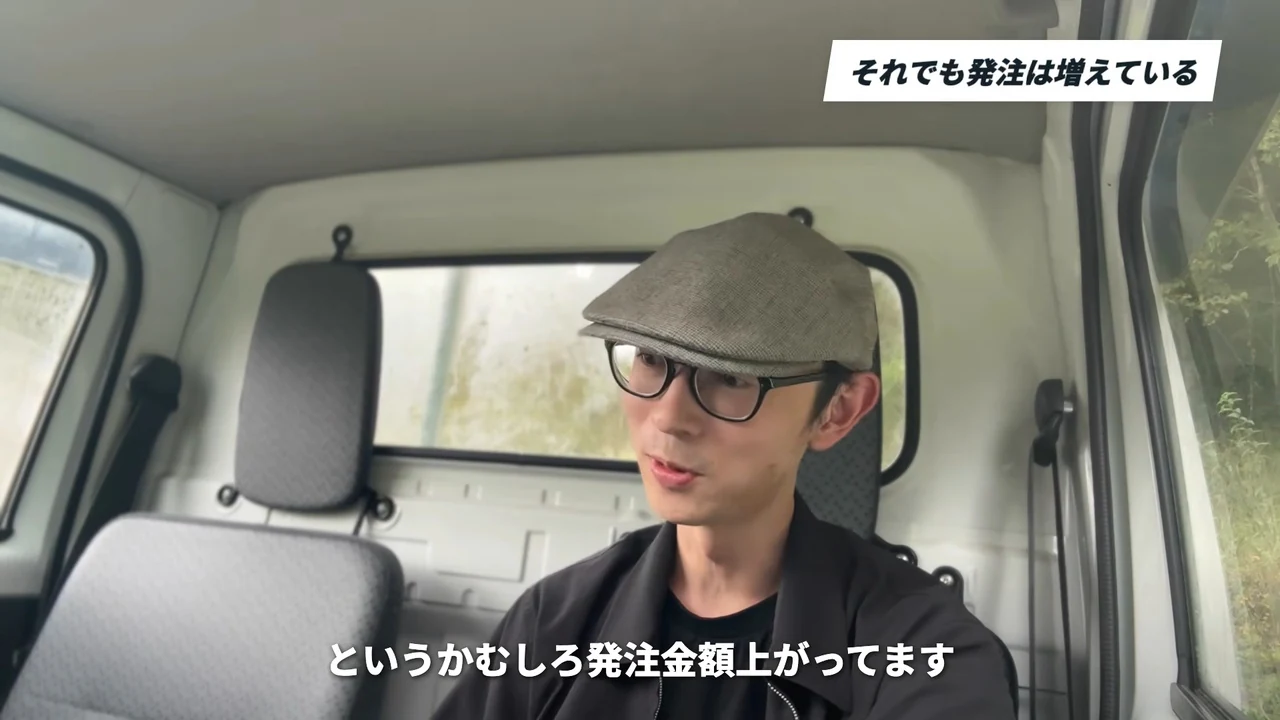 車の中で話すイケハヤさん。右上にそれでも発注は増えているのチャプター表示があり、下の字幕はというかむしろ発注金額上がってます