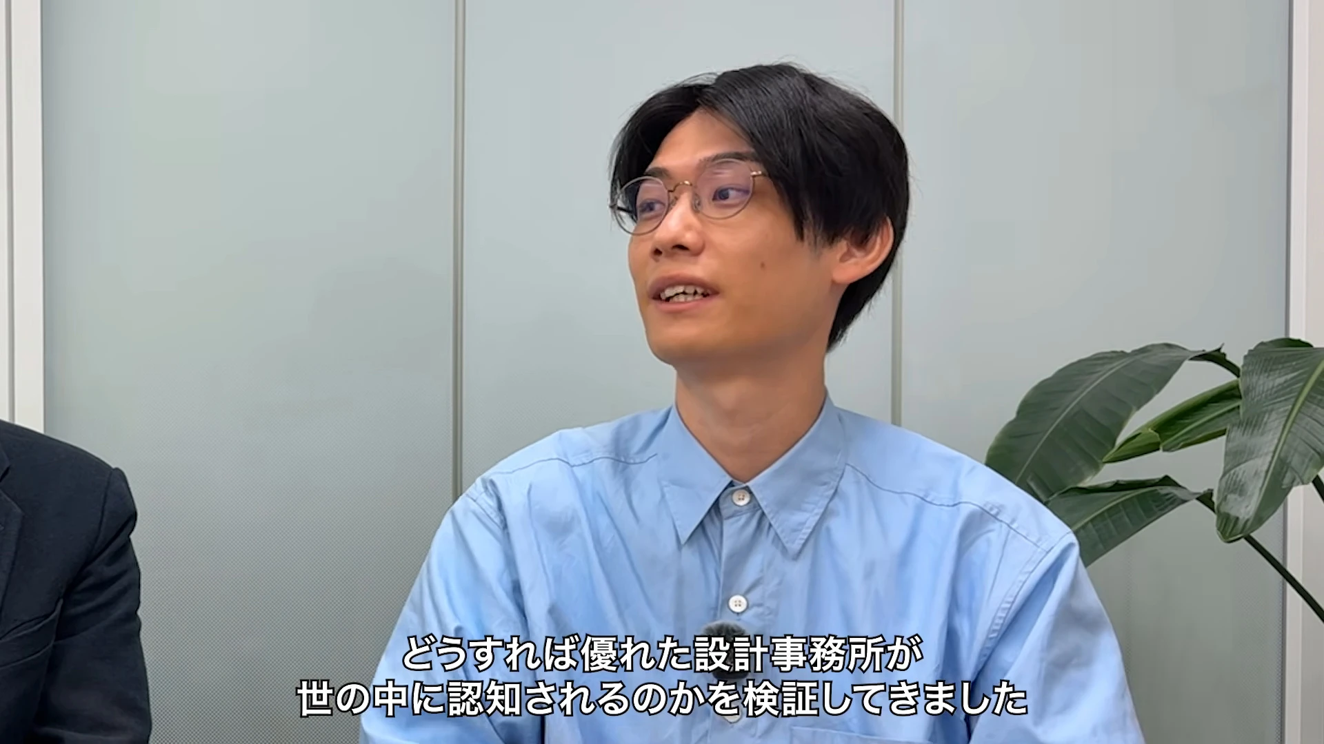 対談動画の場面。右の青いシャツの人が画面いっぱいに映り、話している