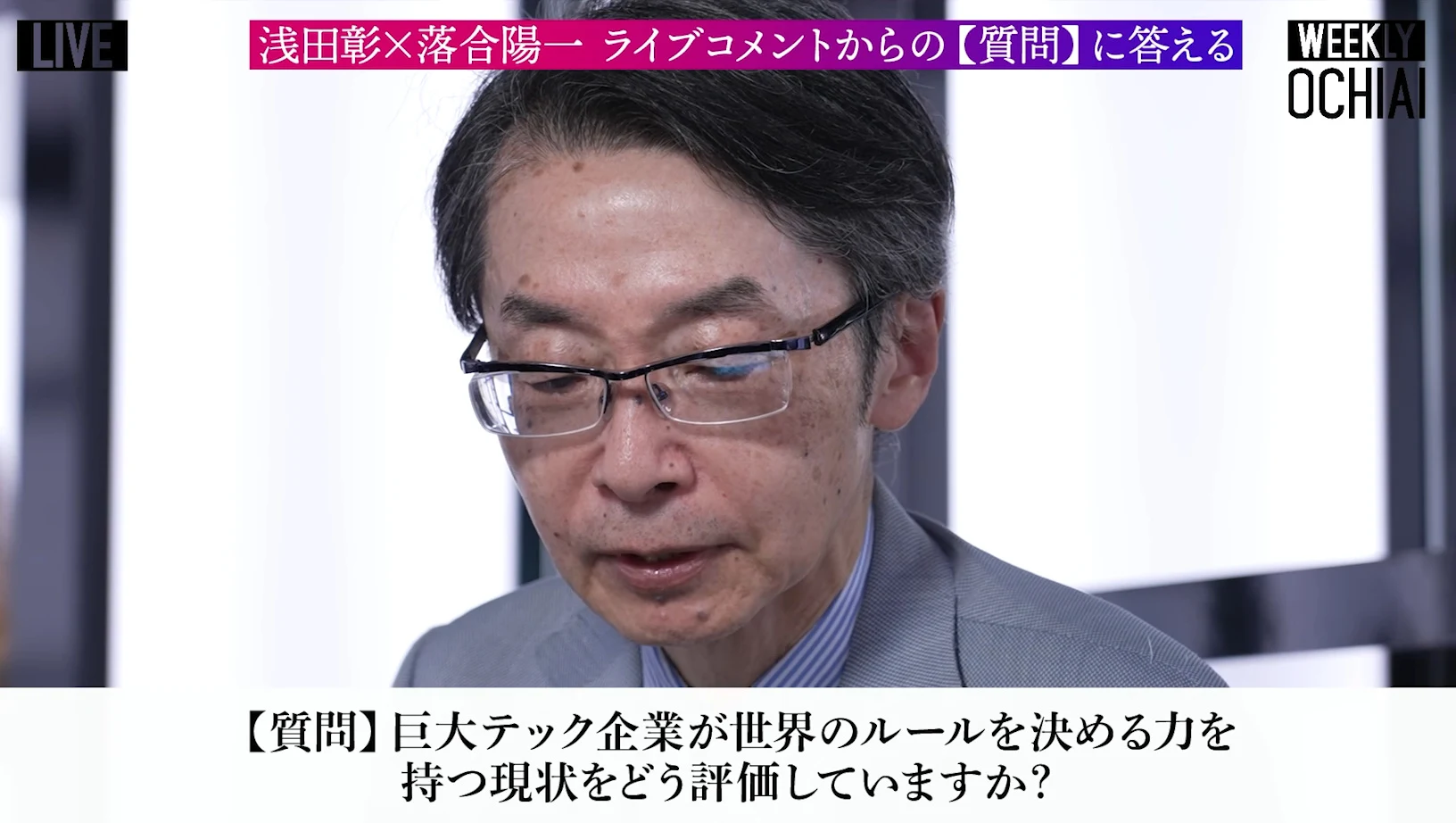 画面上にライブコメントからの質問に答えるの帯、下に巨大テック企業が世界のルールを決める力を持つ現状をどう評価していますかの質問が出て、青灰色のジャケットの人物がうつむいて話す動画の場面