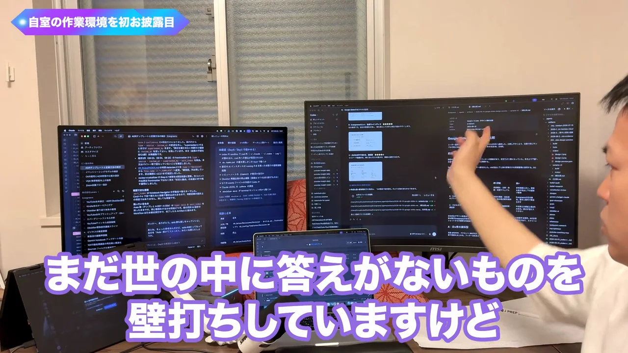動画キャプチャ: 作業部屋で右のモニターの前で手を動かしながら、「まだ世の中に答えがないものを壁打ちしていますけど」と話す画面(25:08頃)