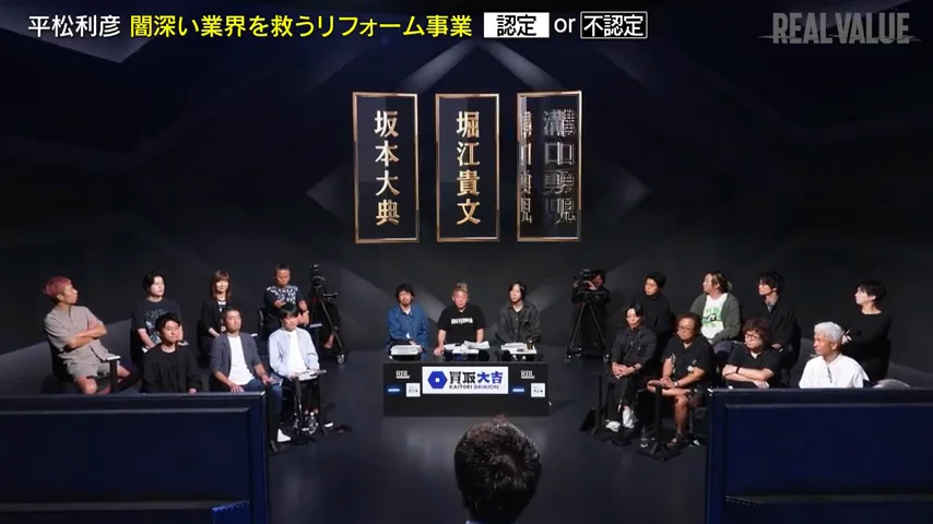 動画キャプチャ: 出演者席の全景に「認定 or 不認定」の表示が出る場面の画面（69:35頃）